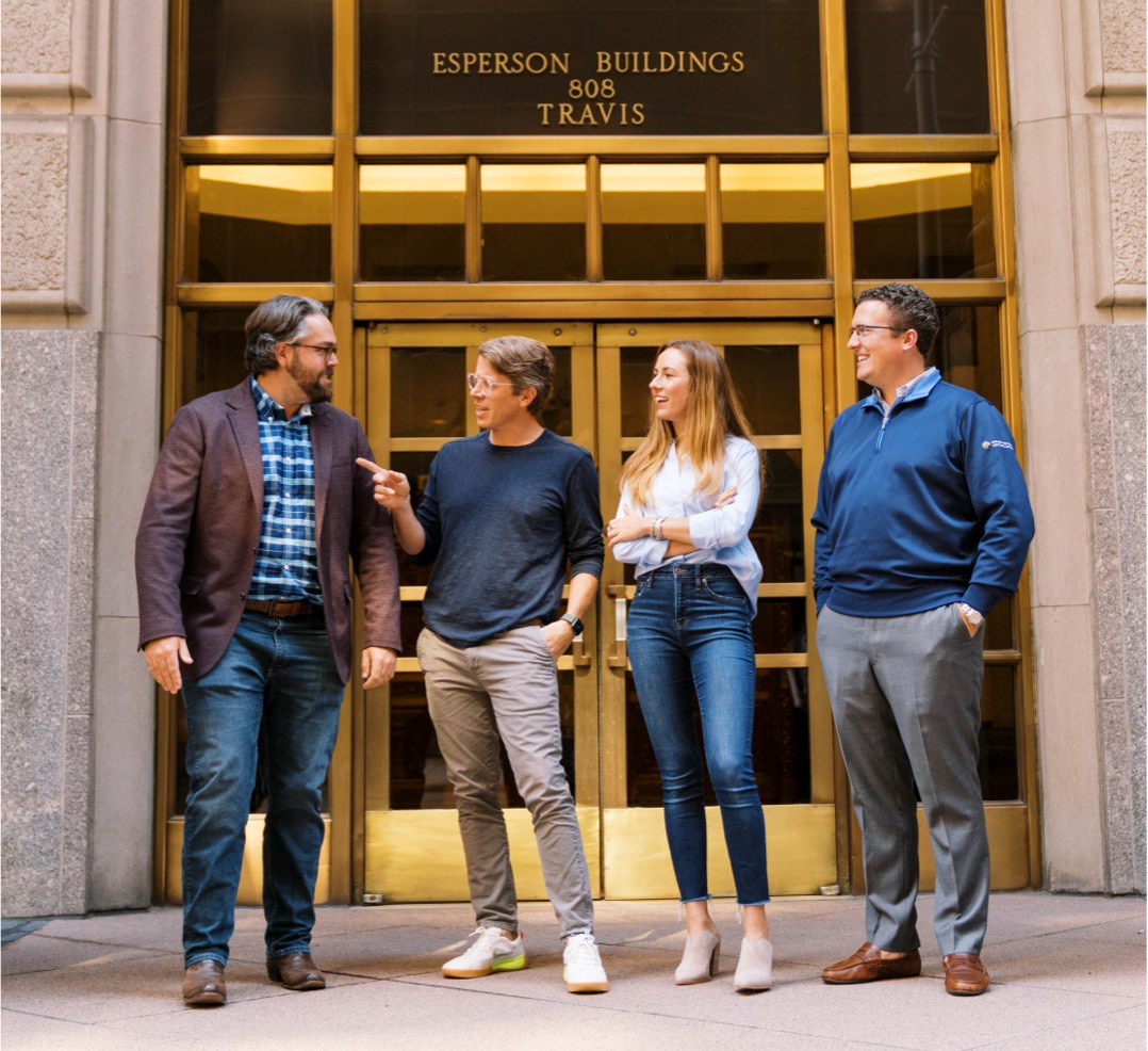a photo of 3 men and 1 woman in business-casual clothing standing in front of a brass highrise entrance labeled Esperson Buildings