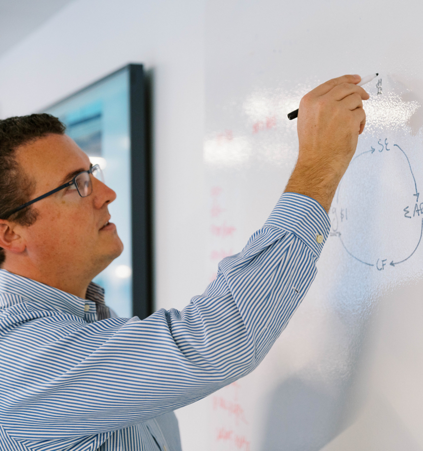 a photo of a man drawing a diagram on a whiteboard